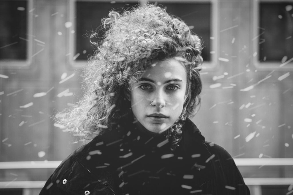 Zwart en wit portret van vrouw met krullen in de sneeuw